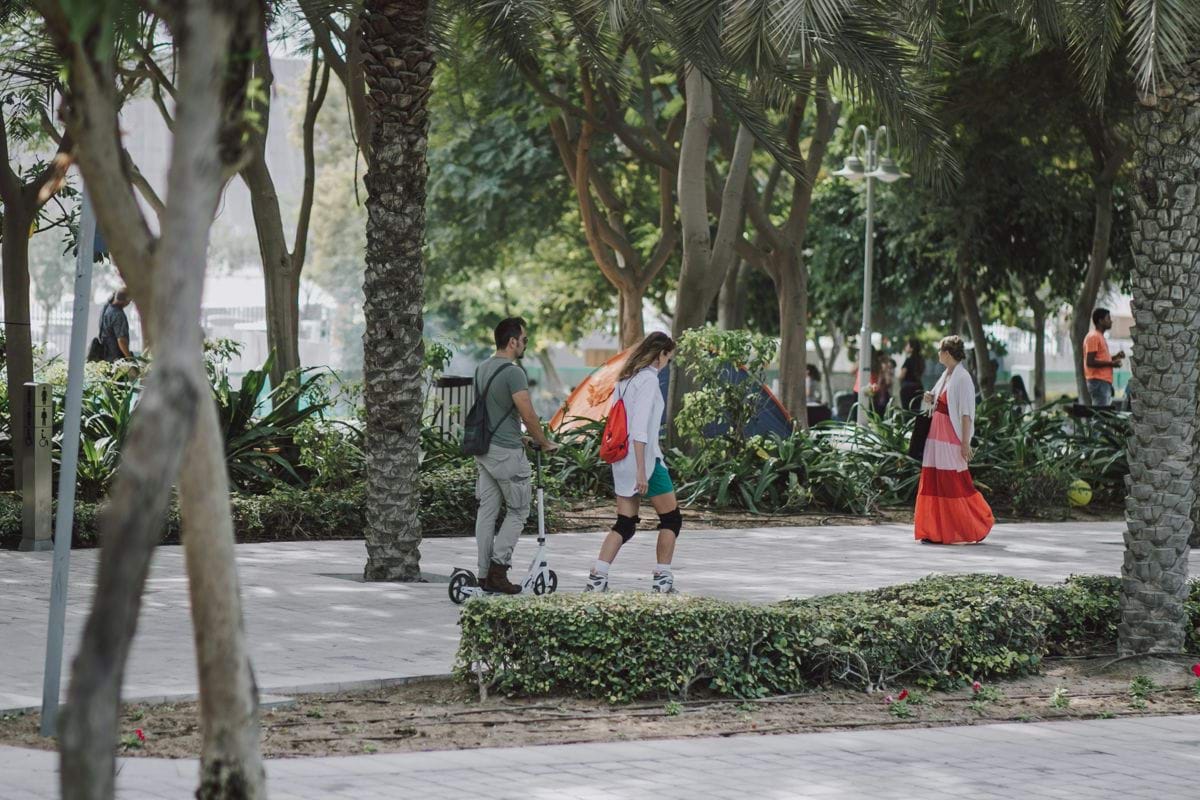 a group of people walking down a sidewalk next to trees