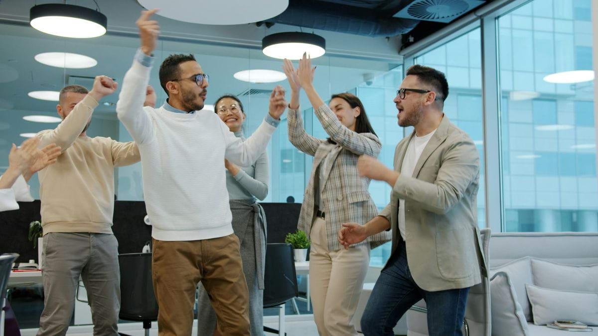 A diverse group of colleagues celebrating success in an office.