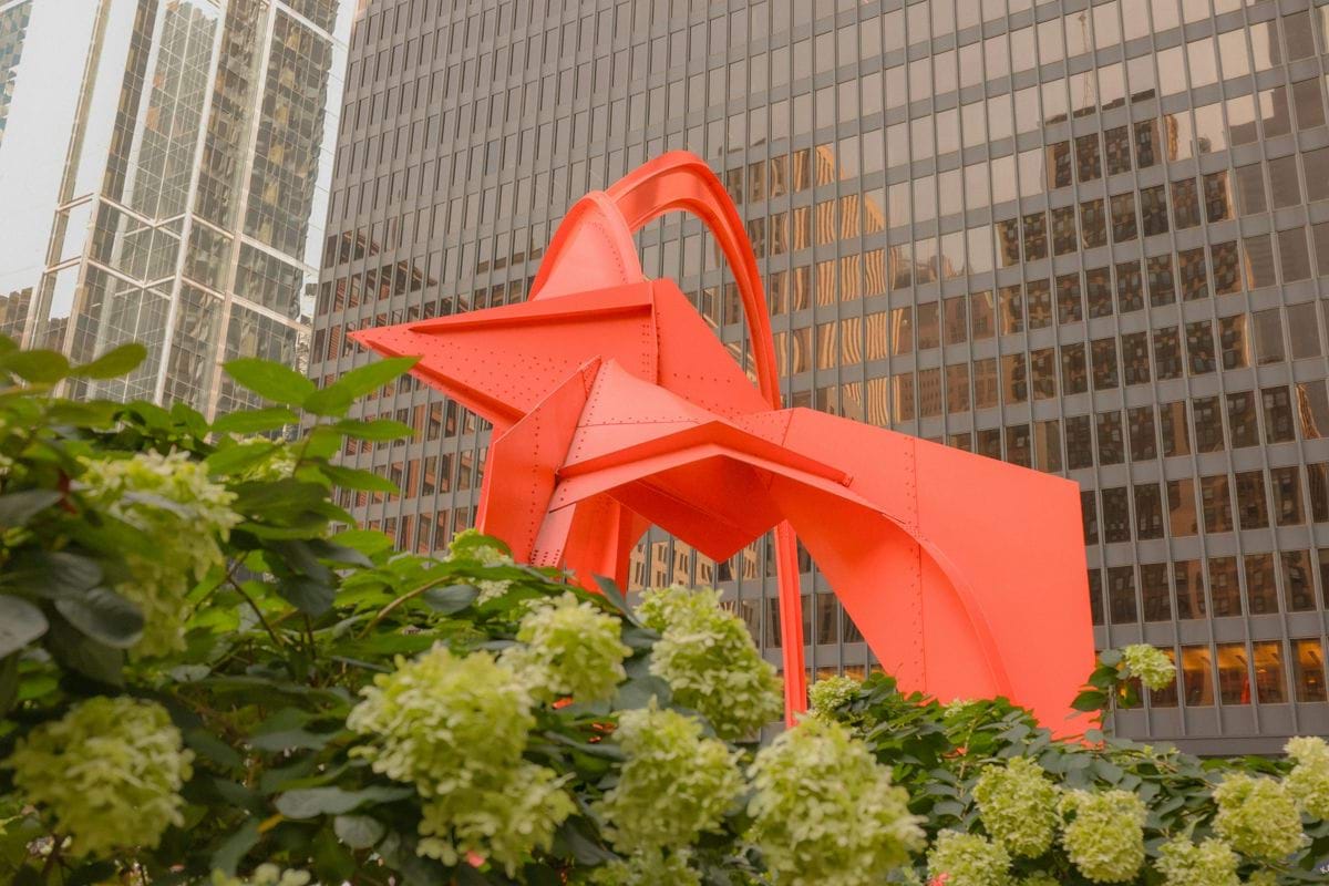 a large red sculpture in front of a tall building