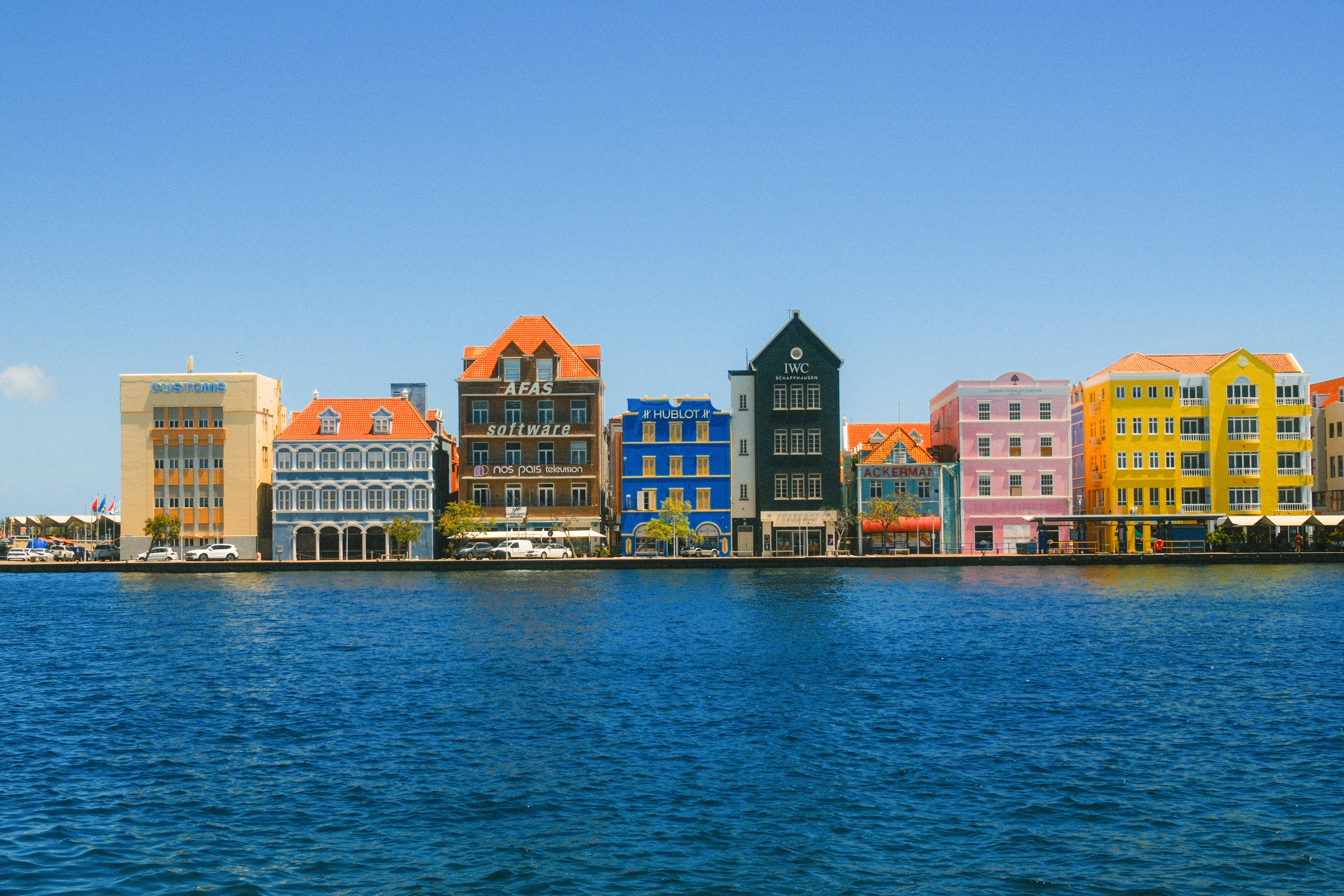 Colorful buildings line a waterfront under a clear sky