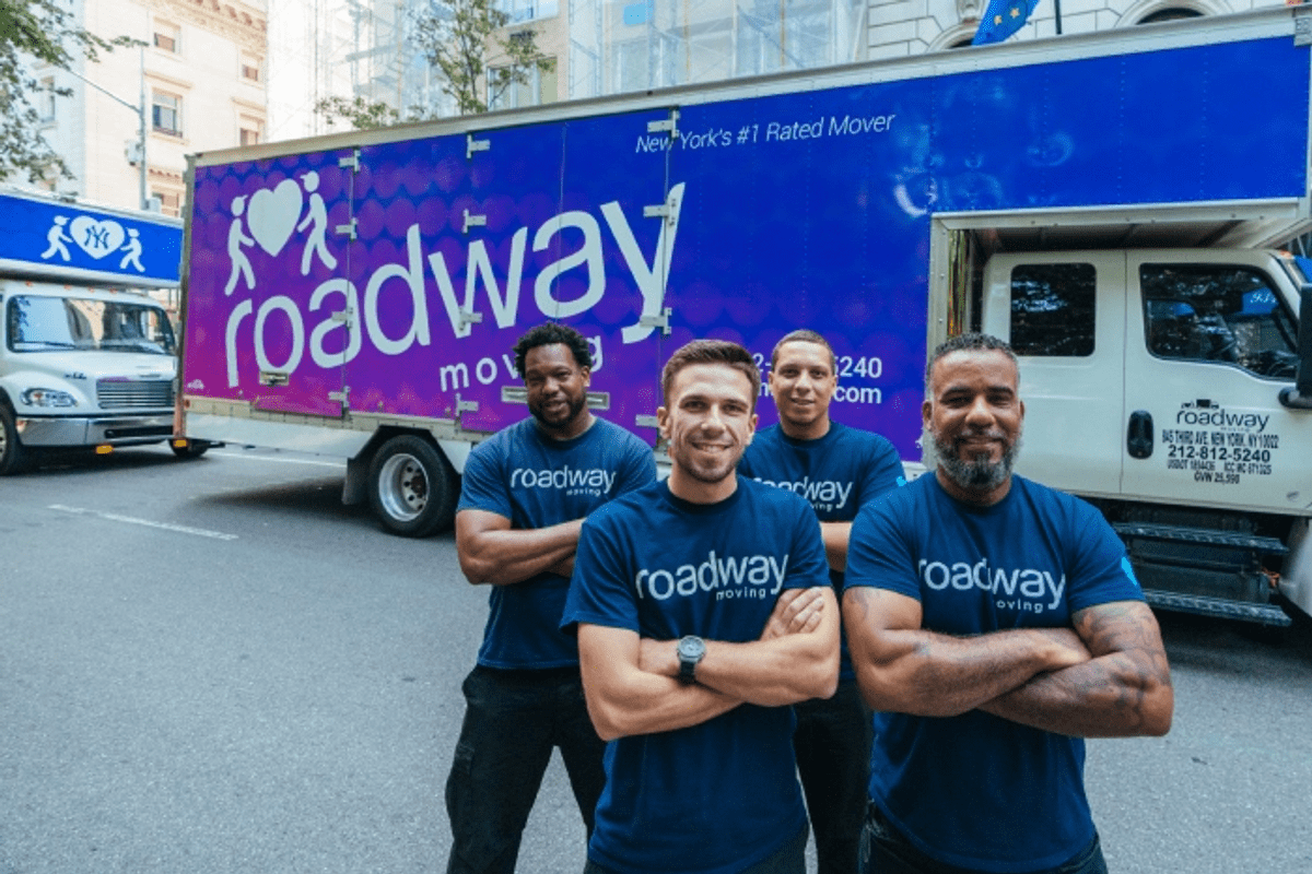 Roadway Moving's crew in front of two Roadway Moving trucks