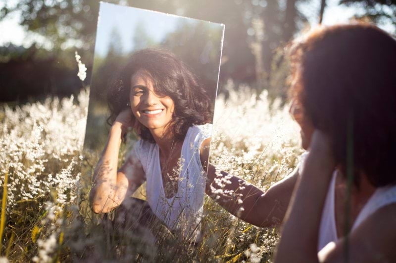 woman in blue and white floral shirt holding her face
