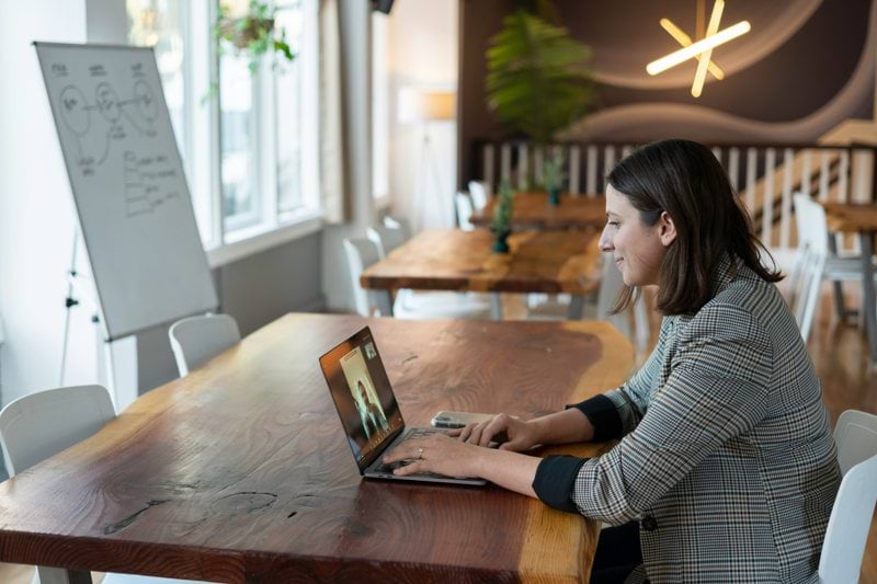 woman in gray and white striped long sleeve shirt using silver macbook