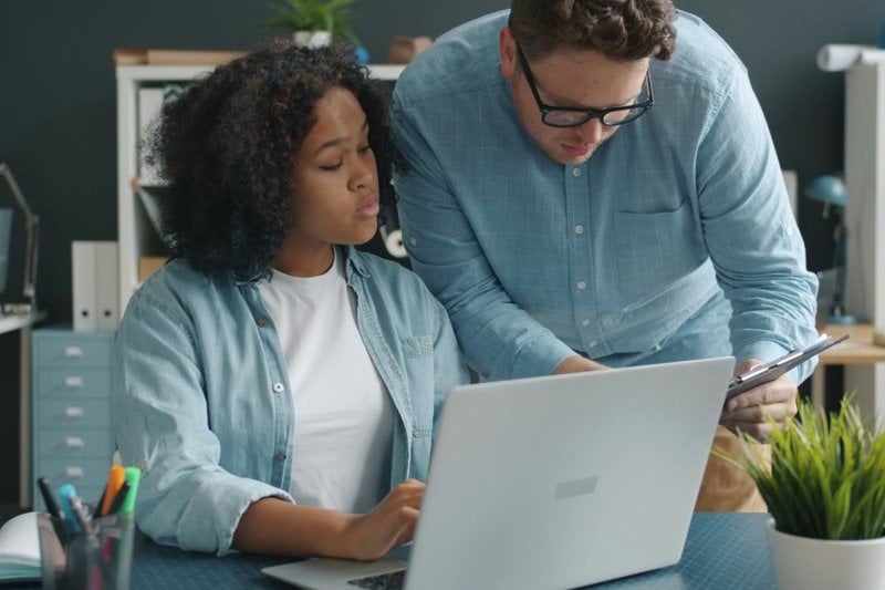 Two colleagues collaborating on a project at a desk.