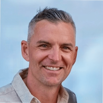 Porträtt av en medarbetare, David, på Advania, leende mot en blå bakgrund.