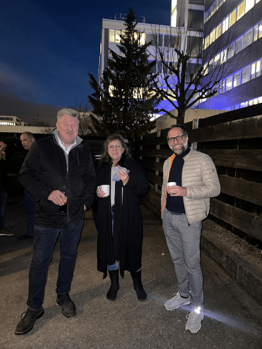 3 Personen stehen zusammen und eine isst eine Wurst