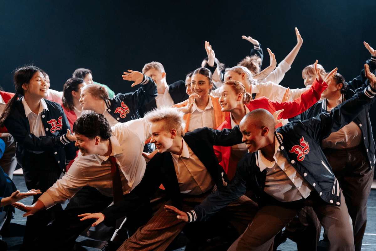 Group of students dressed in colourful clothing striking a pose on stage
