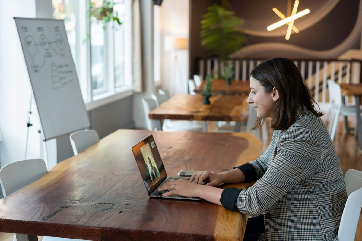 woman in gray and white striped long sleeve shirt using silver macbook