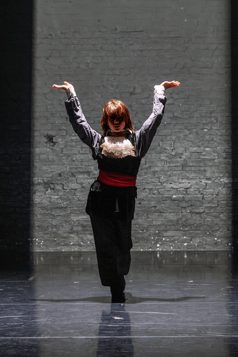 Dancer on stage striking a pose against a dark backdrop