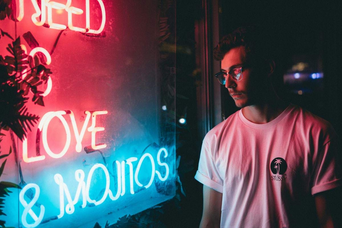 man standing near red and blue neon signage