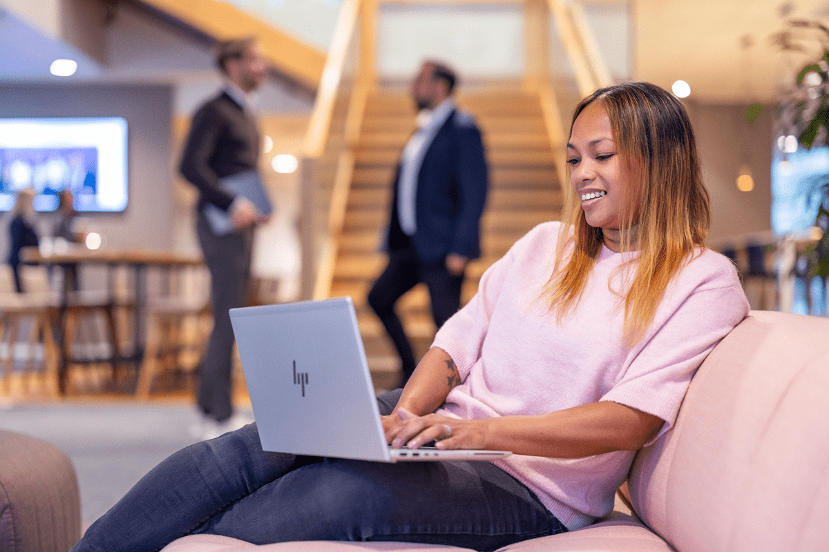 Leende medarbetare framför datorn i soffan