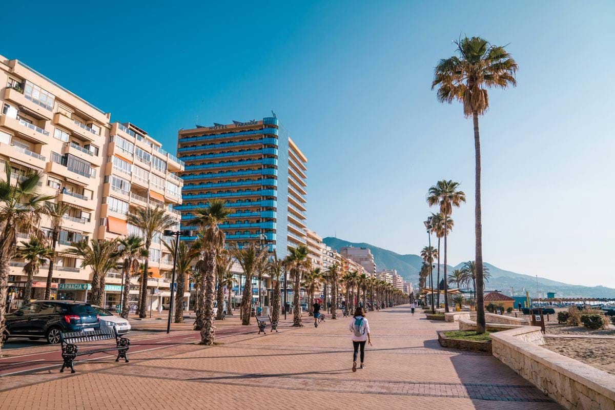 a man walking down a street next to tall buildings