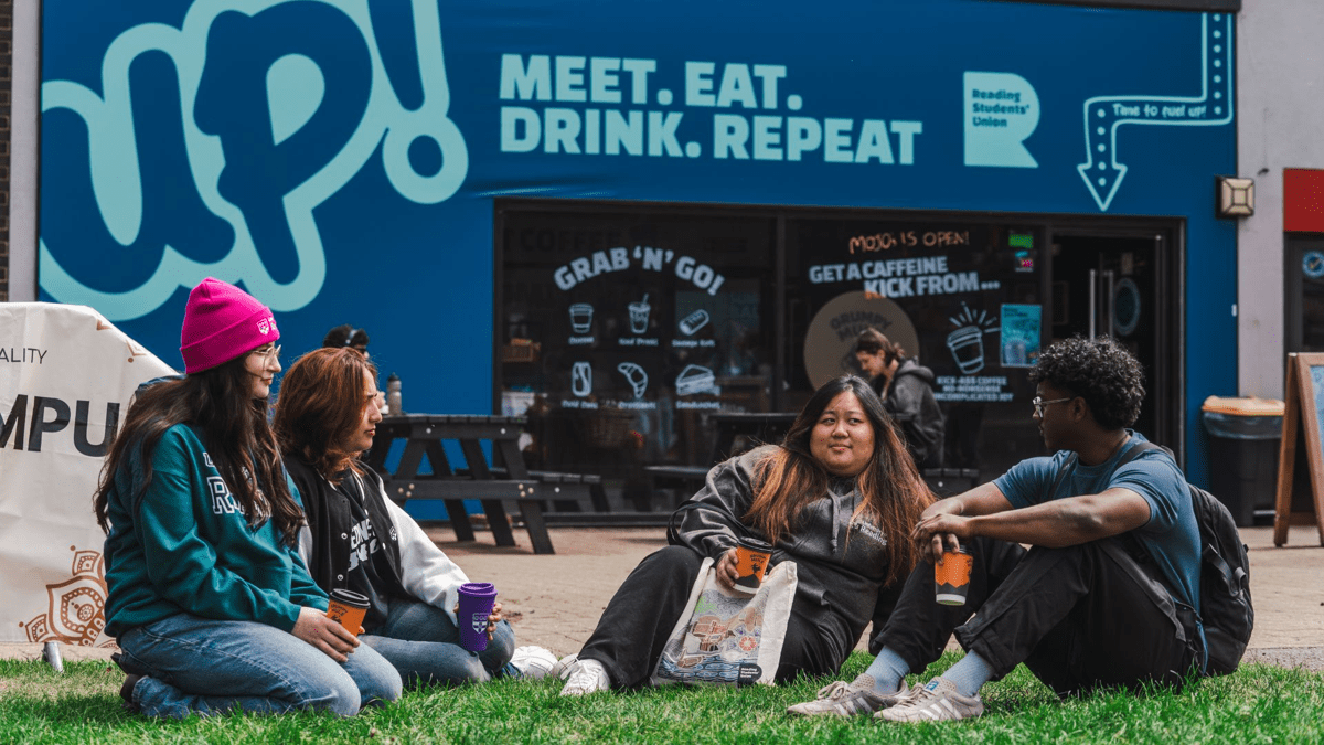 Students sitting on grass outside of the students' Union coffee shop
