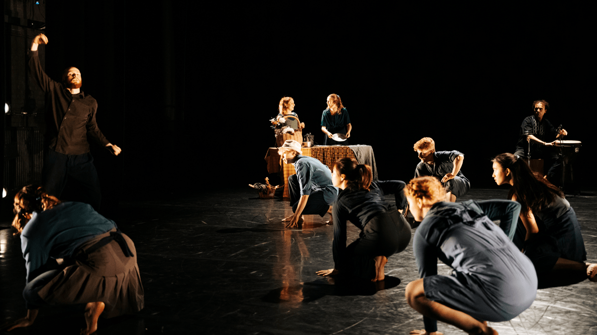 Image of a group of dancers on one knee facing upstage left in dim lighting.