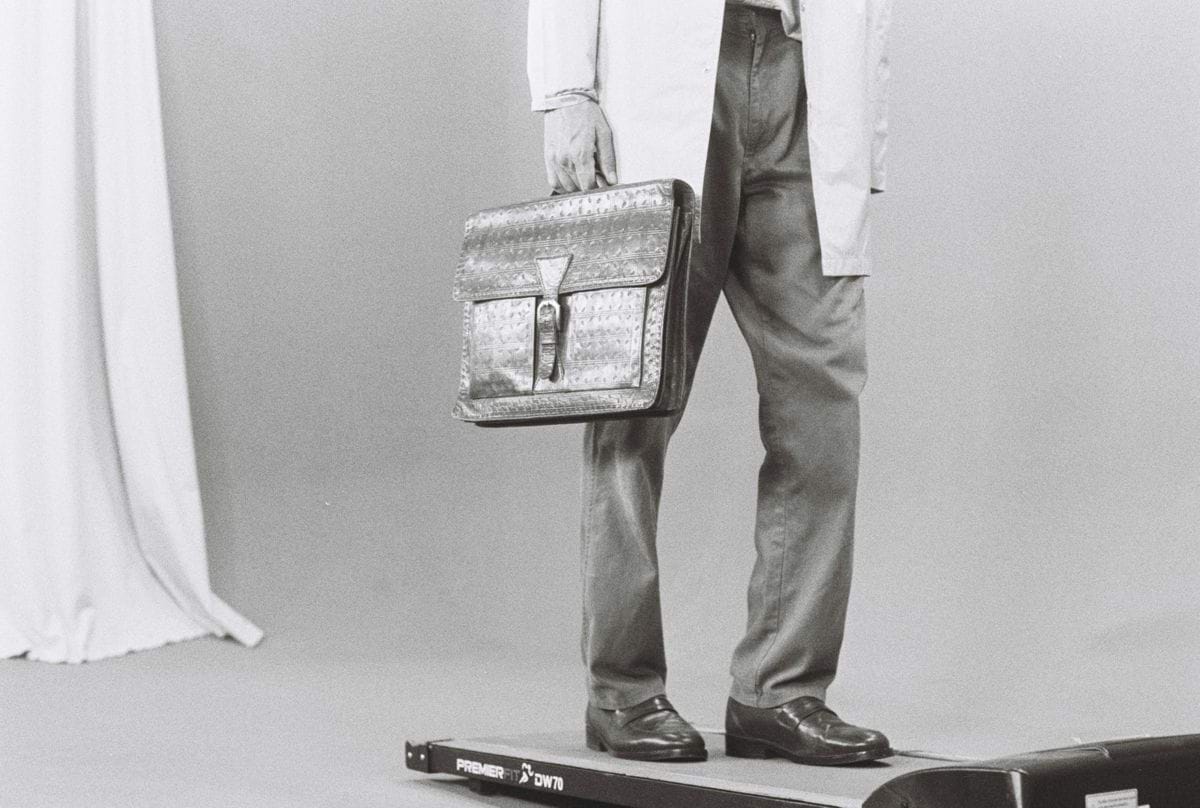 Man in lab coat holding briefcase on scale