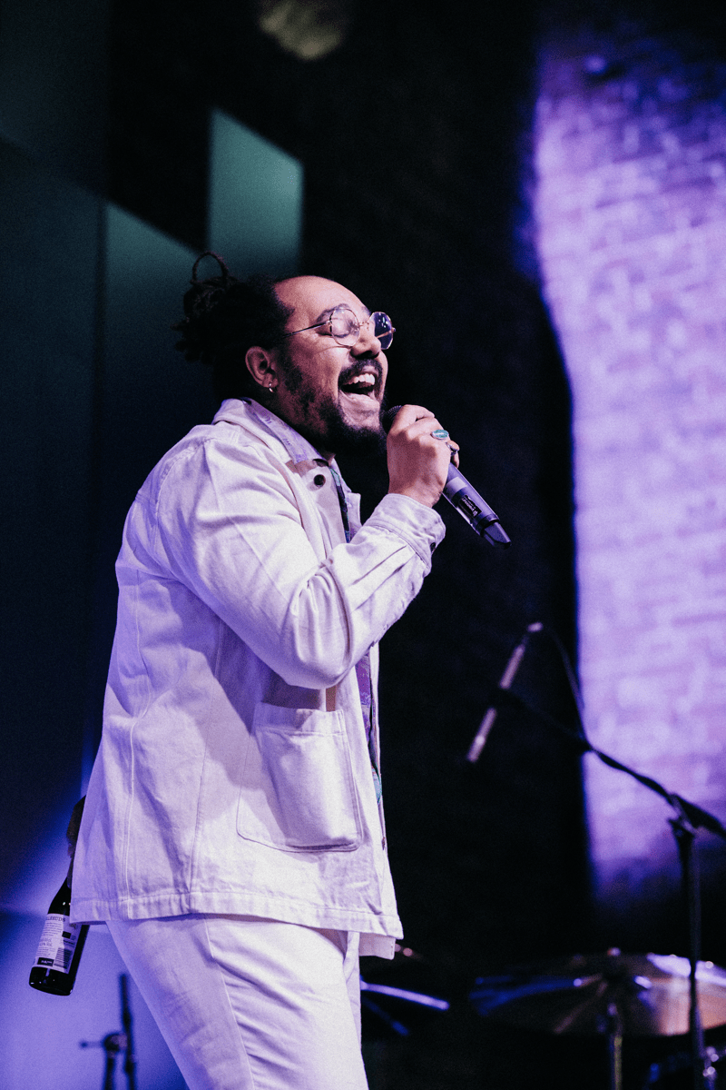 An employee standing on stage singing into the mic. There is a light purple lighting behind them.