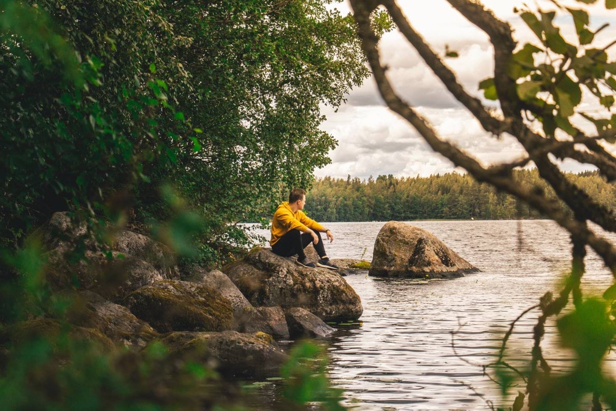 man sitting on rock beside river