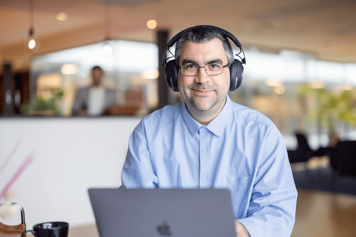Man med hörlurar sitter vid laptop i kontor.
