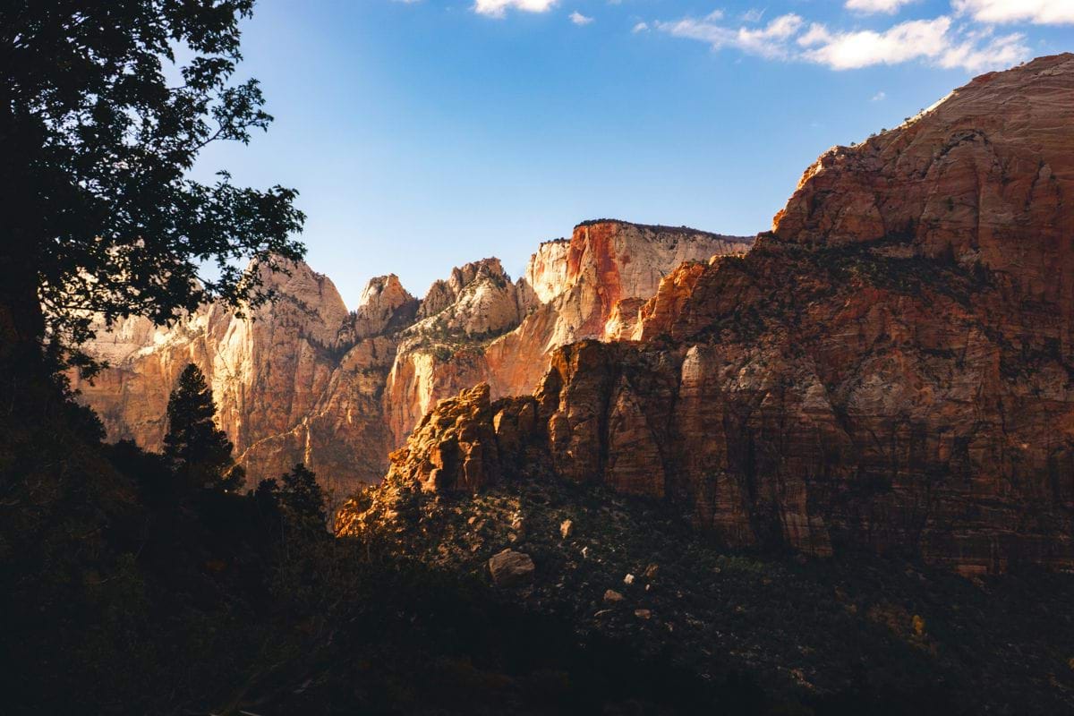 Sunlight illuminates dramatic sandstone cliffs under a blue sky.