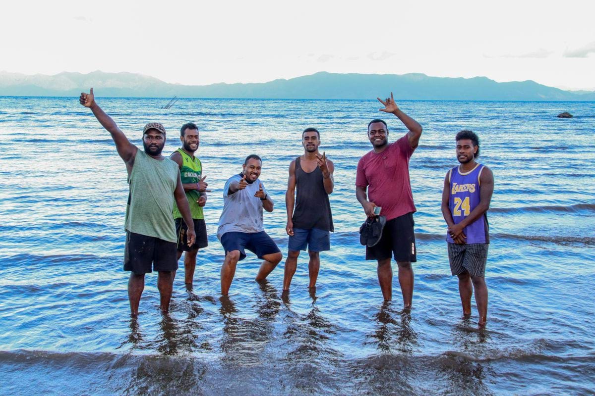 a group of men standing on top of a beach next to the ocean