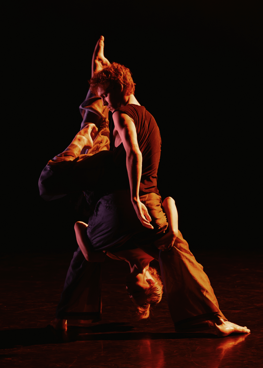 Two students across a dark background, draped across each other