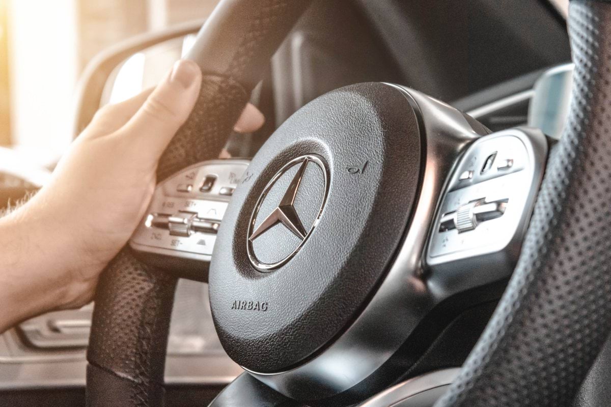 person holding Mercedes-Benz multifunction steering wheel