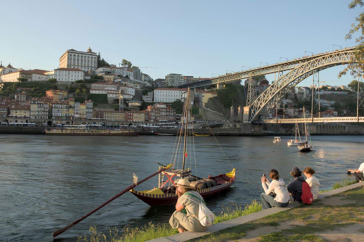 A group of people sitting on the side of a river