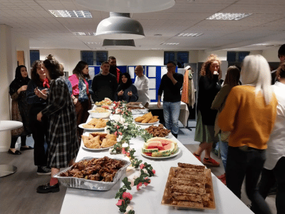 People gathered around a table of food at the Barca-Leeds Iftar event