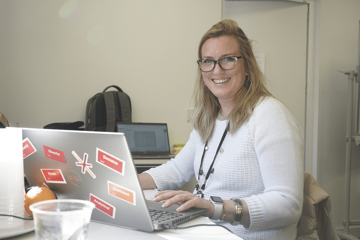 Woman smiling in camera with laptop full of SD Worx stickers