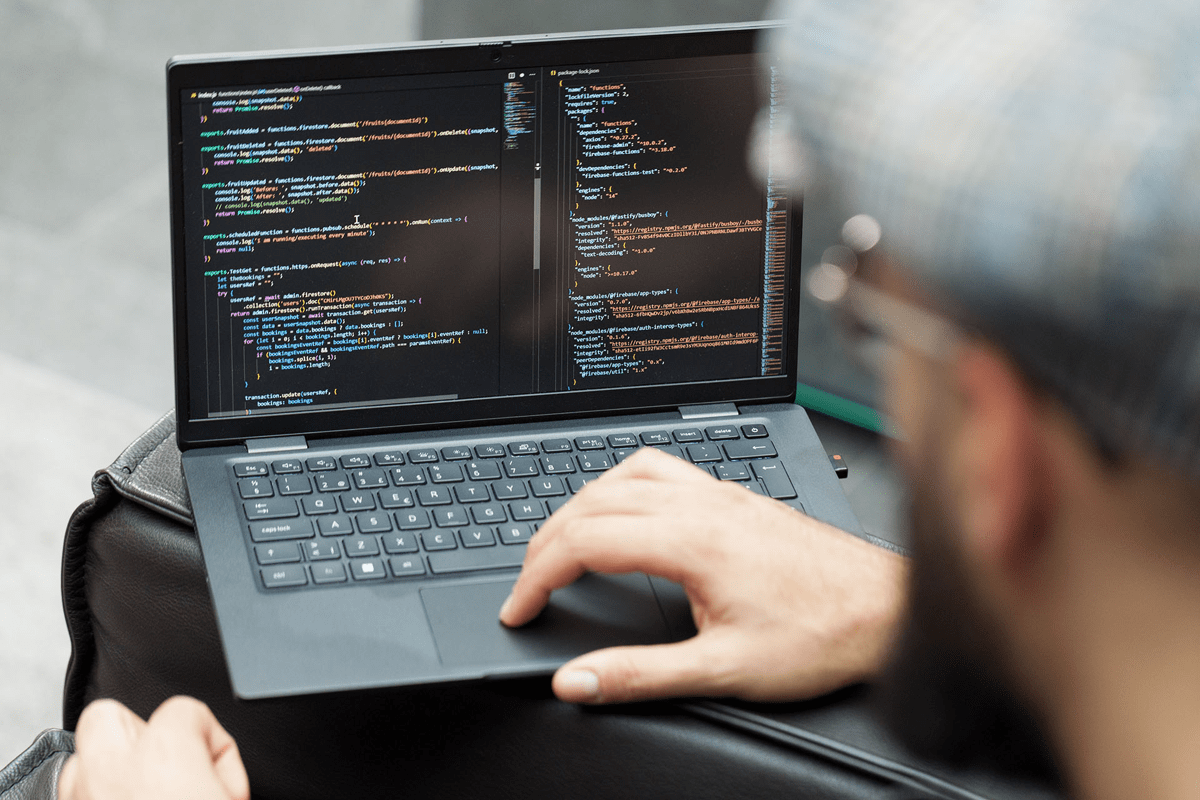 Prson working on a laptop displaying computer code