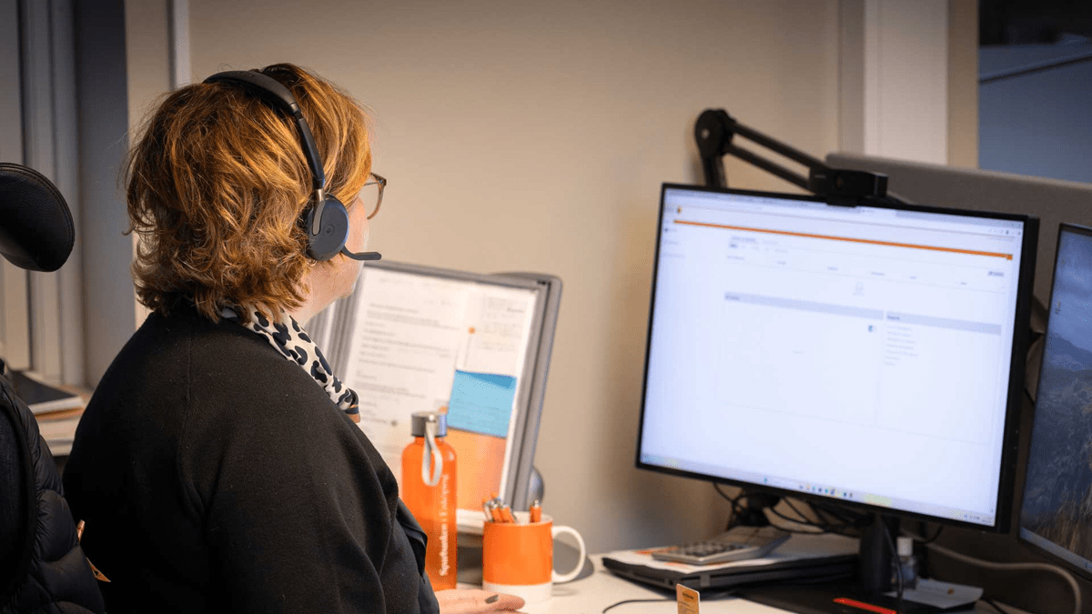 Kvinna med headset jobbar vid sin dator