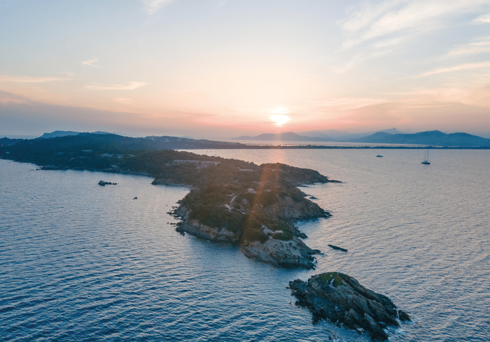 Bras de terre avec un magnifique coucher de soleil à l'horizon, entourée par la mer.