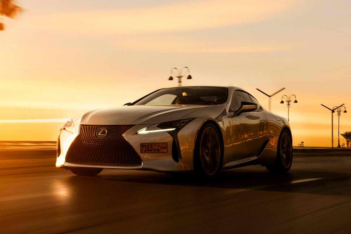 a silver sports car driving down a road
