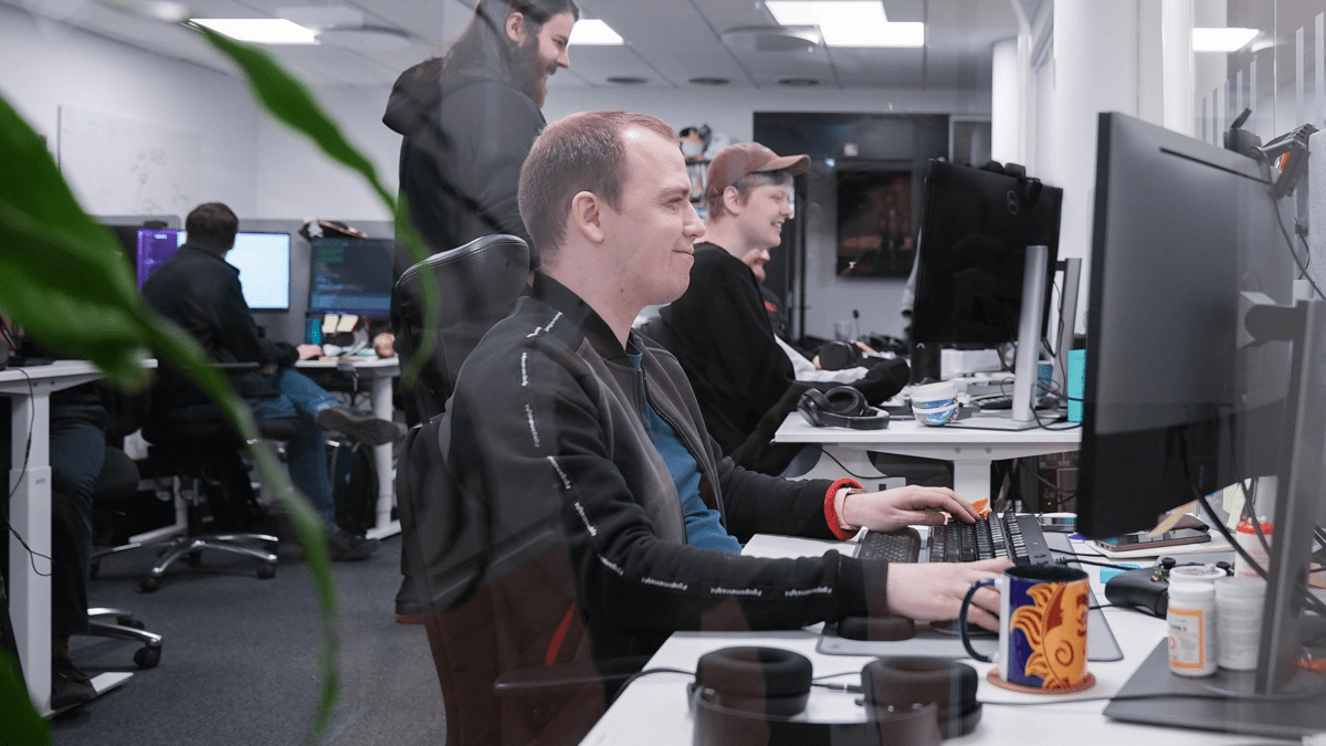 Smiling Game Developers working in collaboration at their desks