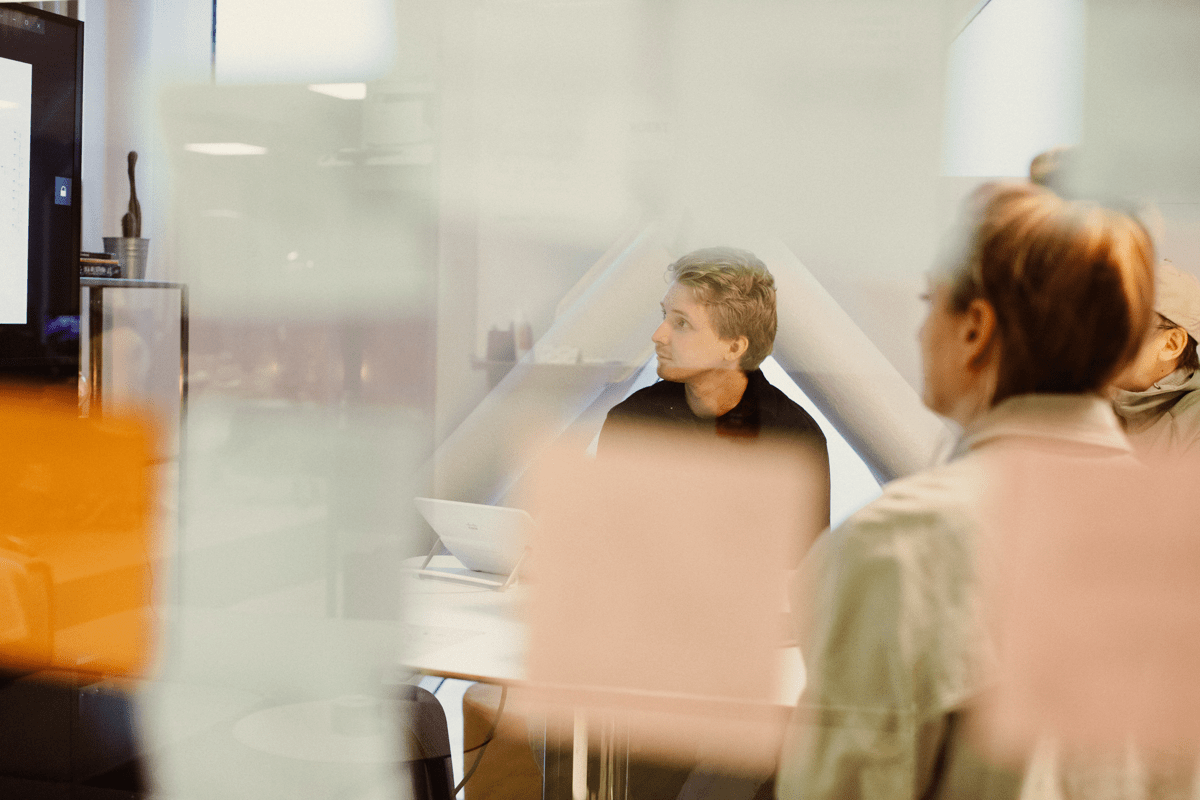 A meeting in a room with glass walls, there are post-it-notes on the walls