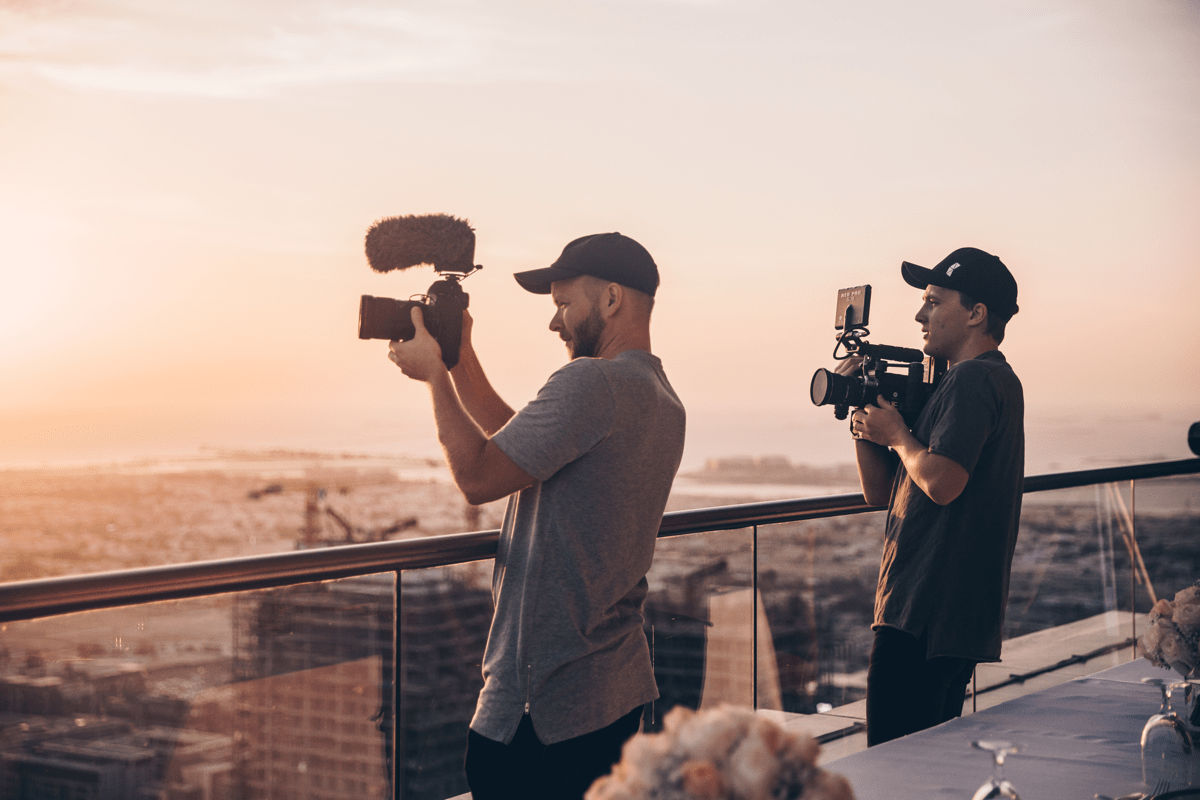 Two creators on a rooftop shooting shots on their camera of the scenery around them