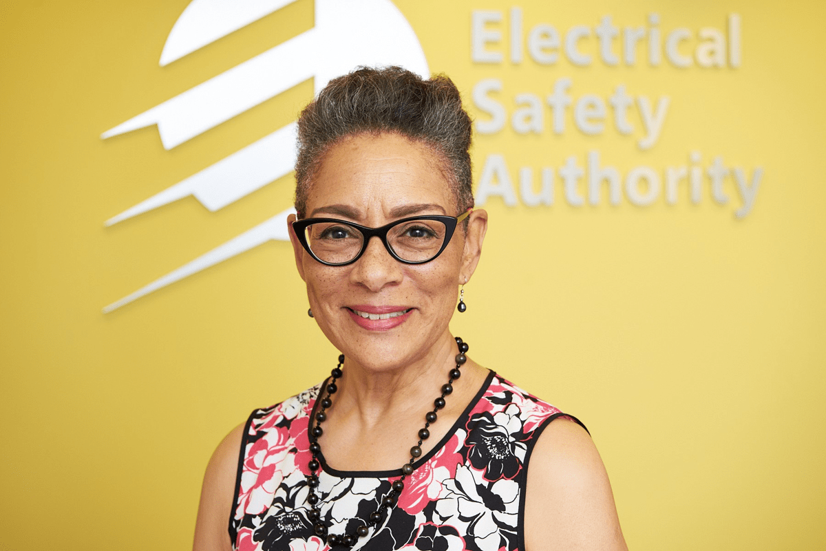 A smiling employee wearing a multi-coloured blouse poses in a bright, modern office.