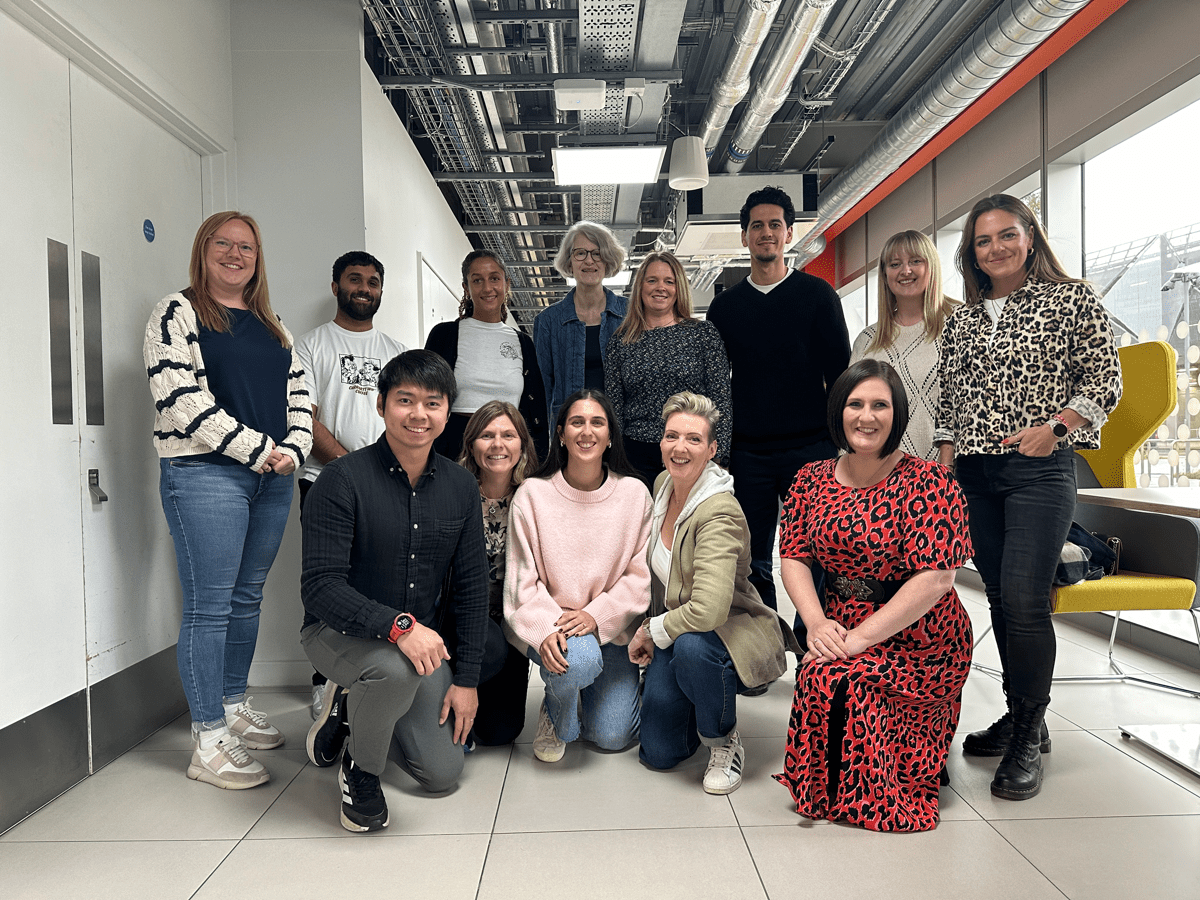 Staff photo of 13 members of UKAD's EDI Working Party together. 5 along the front are on one knee with the others standing behind them