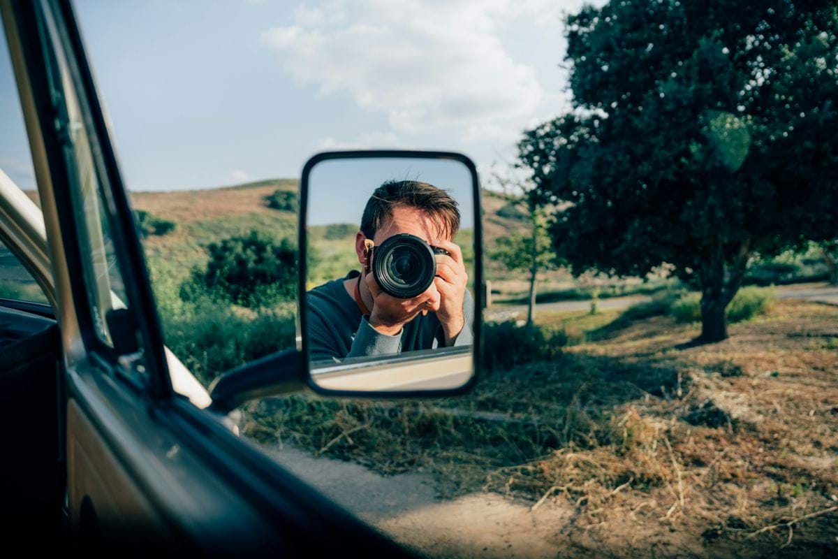 a man taking a picture of himself in a rear view mirror