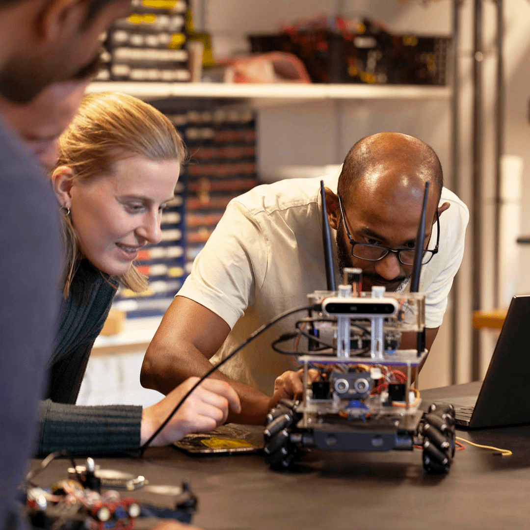 One woman and two men standing around a worktable looking at hardware
