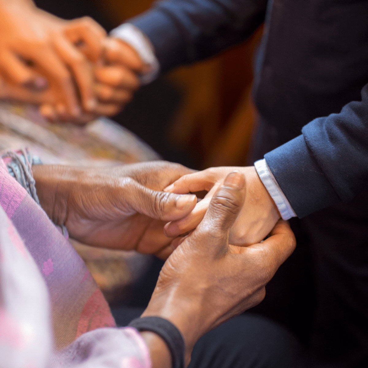 Shot shows one person's hands each being held in the two hands of another person