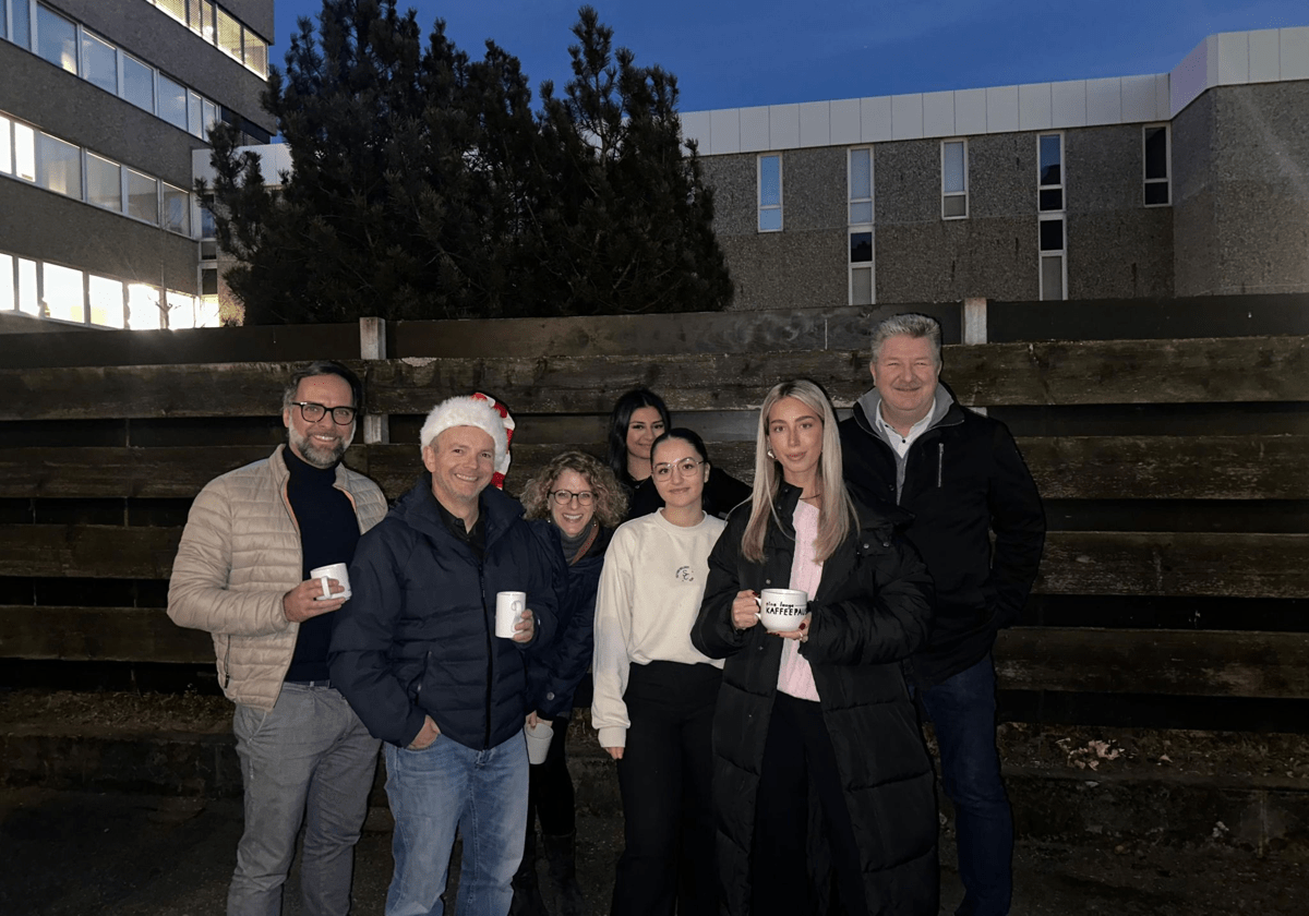 7 Personen stehen für ein Gruppenfoto zusammen und lachen