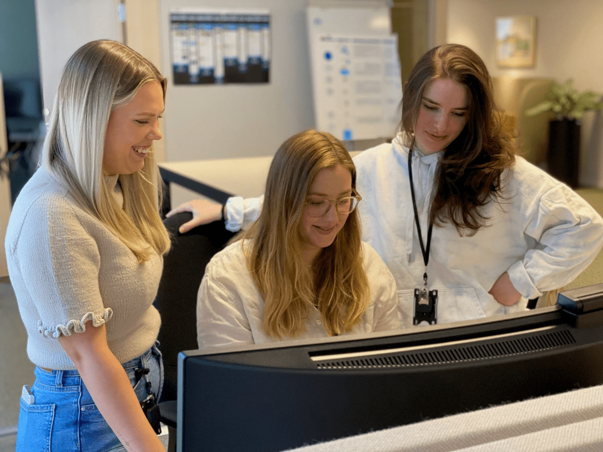 Tre kvinnor runt ett bord med dator i kontorsmiljö