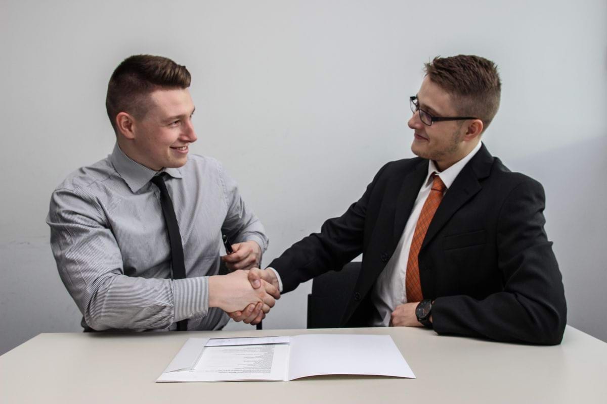 two men facing each other while shake hands and smiling.jpg