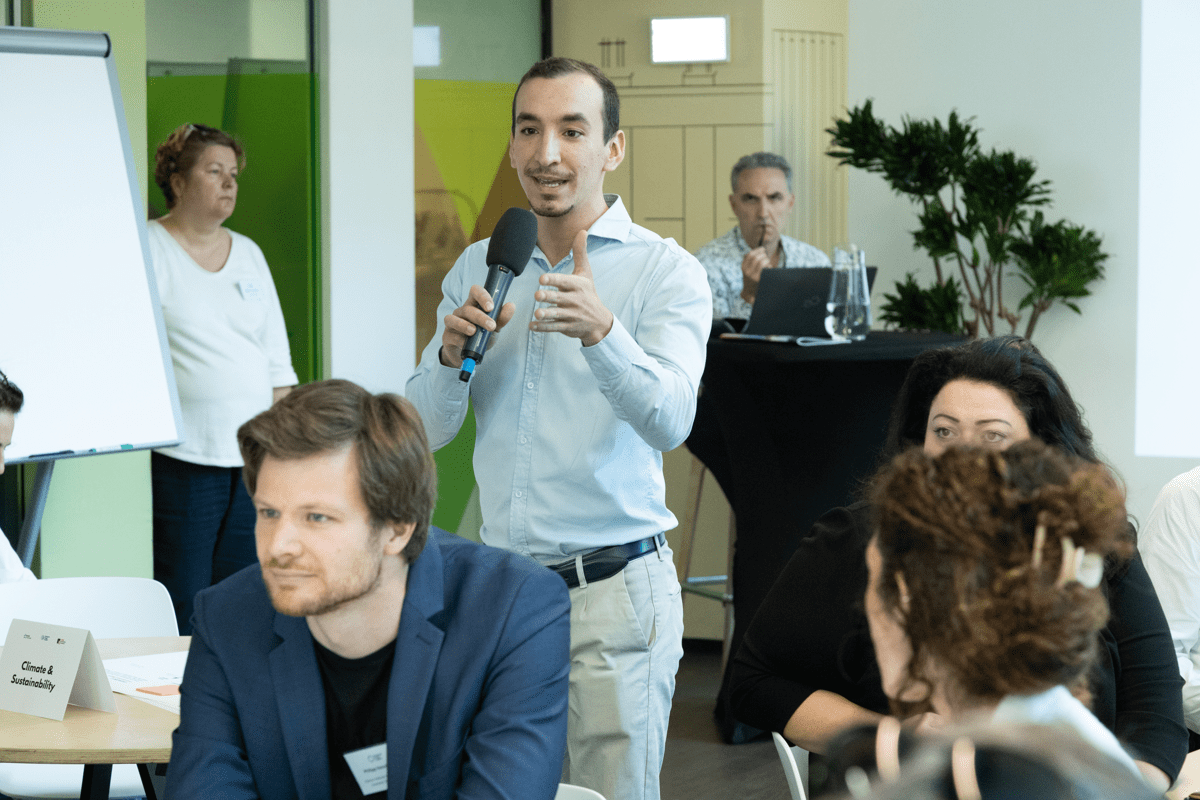 A man speaks into a microphone next to a whiteboard