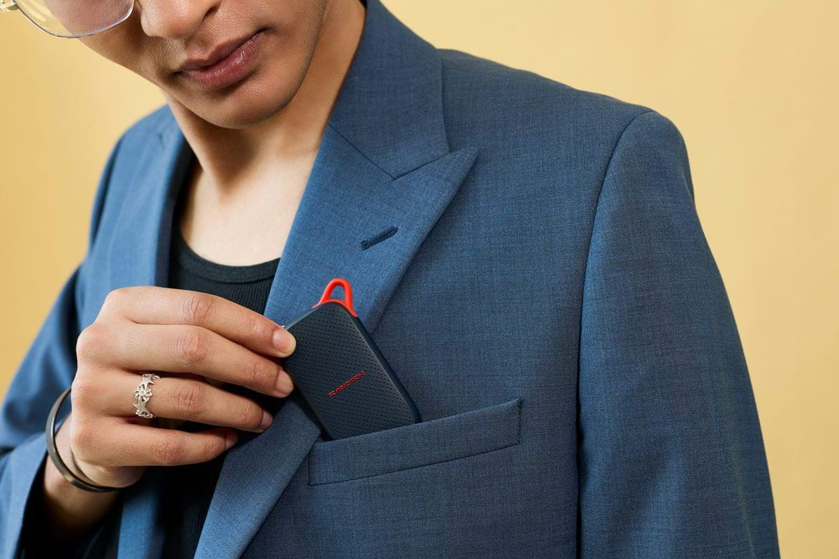 Hand inserting a black electronic device into a blazer pocket