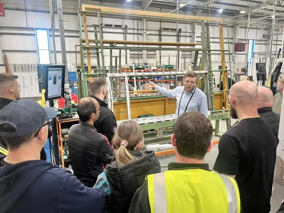 Team gathered around a training window rig on the factory floor