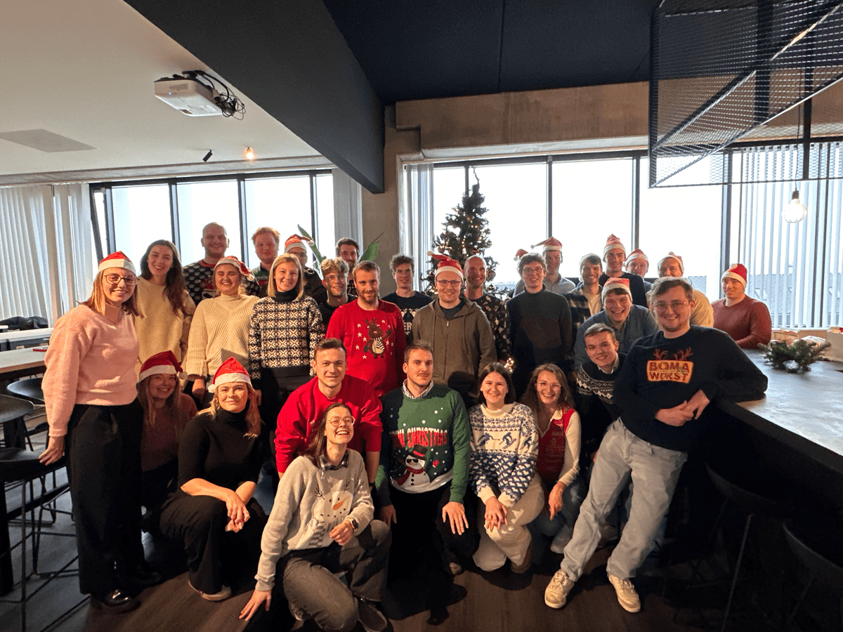 Team van collega's draagt feestelijke kersttruien op kantoor.