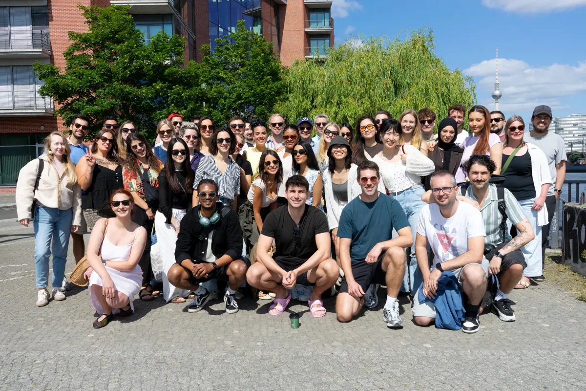A large group of colleagues posing together outdoors during a team event.