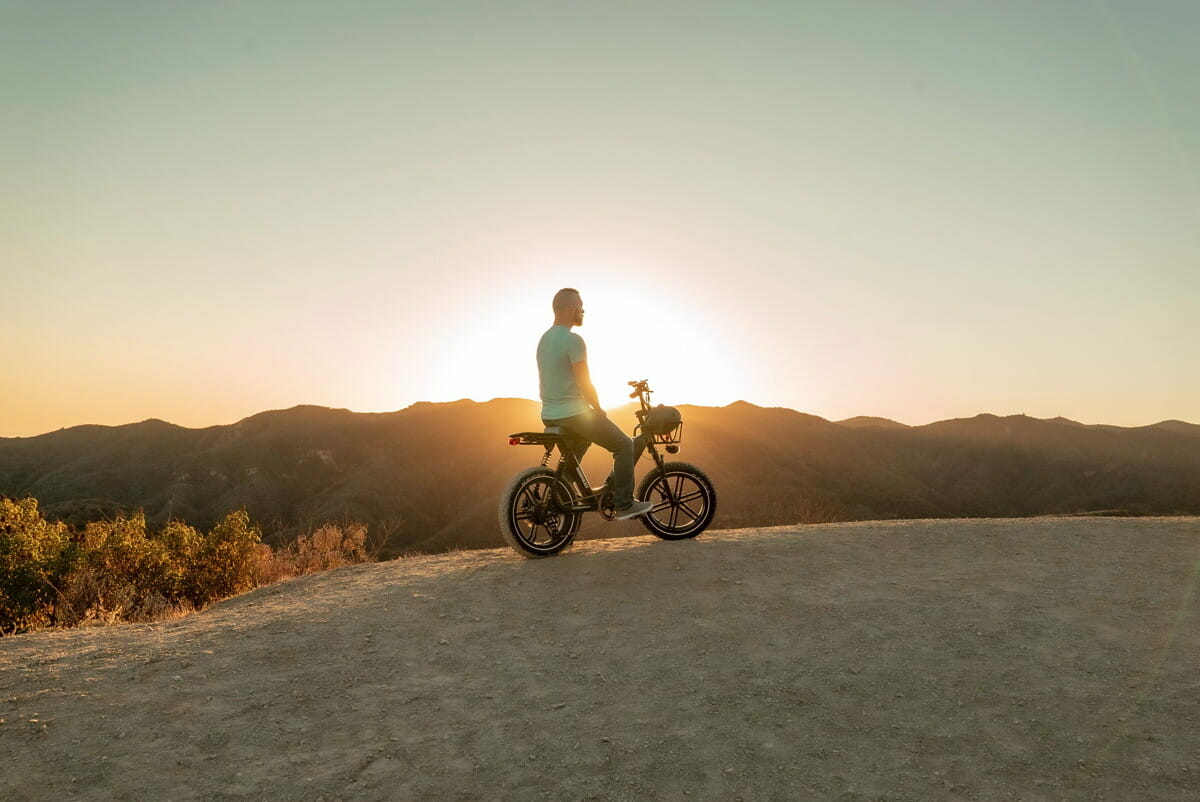 man riding motorcycle on gray sand during sunset